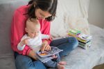 Mutter zeigt Baby Bücher, sitzen auf einer Couch